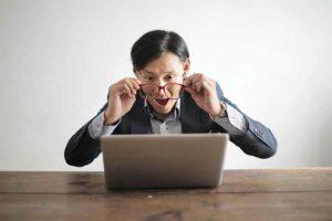 Man Looking Through His Glasses At His Computer, Potentially Admiring The Great User Experience